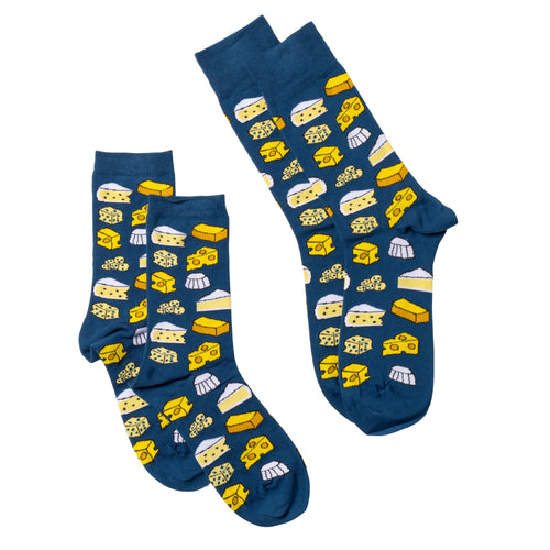 Yellow Owl Workshop cheese crew socks in two sizes, displayed side by side on a white background. Navy blue socks covered in colorful illustrations of cheddar, Swiss, brie, and blue cheese. Food-themed patterned socks available in men's and women's sizes, perfect for cheese lovers and foodie gifts.