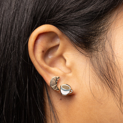 Coffee and croissant mismatched cloisonné stud earrings worn on ear by Yellow Owl Workshop