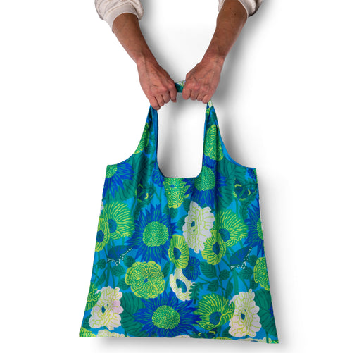 Person holding illustrated floral tote bag with bold oversized cobalt and chartreuse bloom print by Emily Taylor for Yellow Owl Workshop