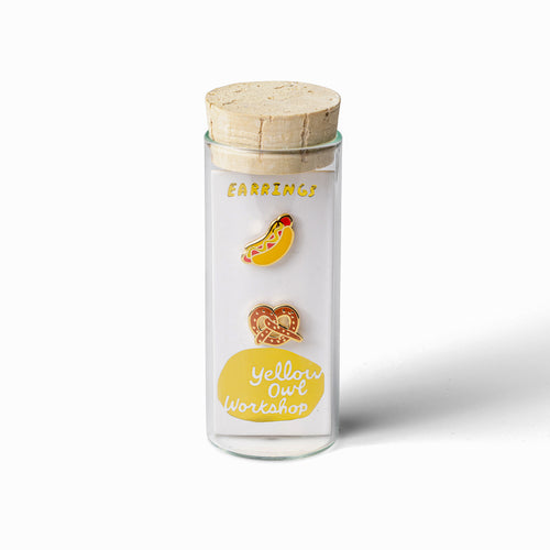 Hot dog and pretzel mismatched cloisonné stud earrings in glass vial packaging by Yellow Owl Workshop