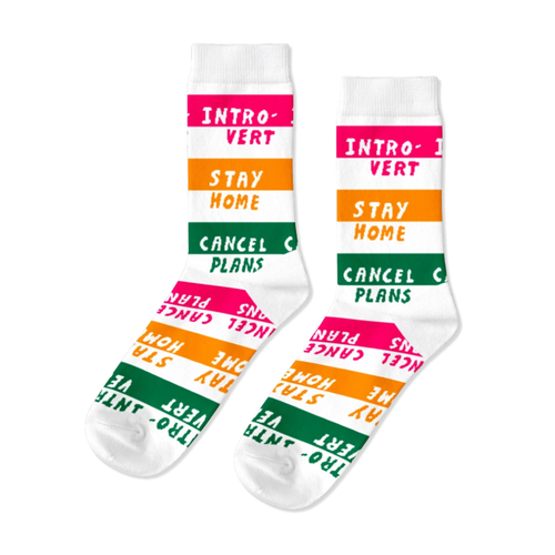 White crew socks featuring Introvert Stay Home and Cancel Plans text in bold pink orange and green stripes by Yellow Owl Workshop