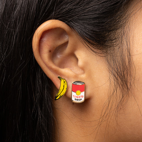 Pop Art Banana and Soup mismatched gold stud earrings worn on ear by Yellow Owl Workshop