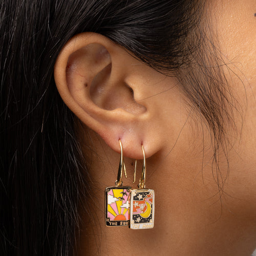 Sun and Moon Tarot mismatched enamel drop earrings worn on ear by Yellow Owl Workshop