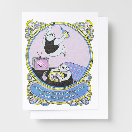 Risograph greeting card with two illustrated sloths lounging together with a retro TV, pizza, and a bottle in an ornate oval frame, text reads Doing Nothing With You Is My Everything on a blue banner