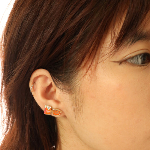 Dutch oven and kosher salt mismatched cloisonné stud earrings worn on ear by Yellow Owl Workshop
