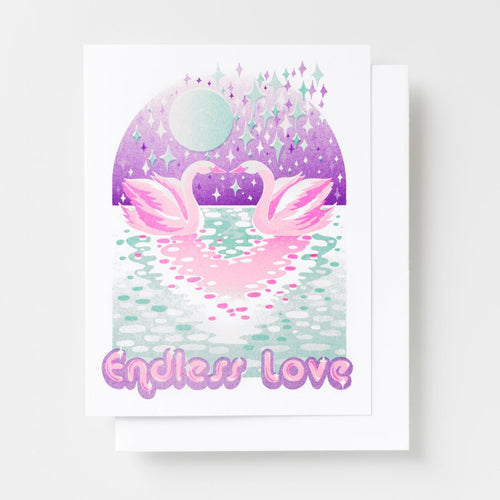 Risograph greeting card with two illustrated pink swans facing each other on a sparkling moonlit lake with a purple sky full of stars and diamonds, text reads Endless Love in pink bubble lettering