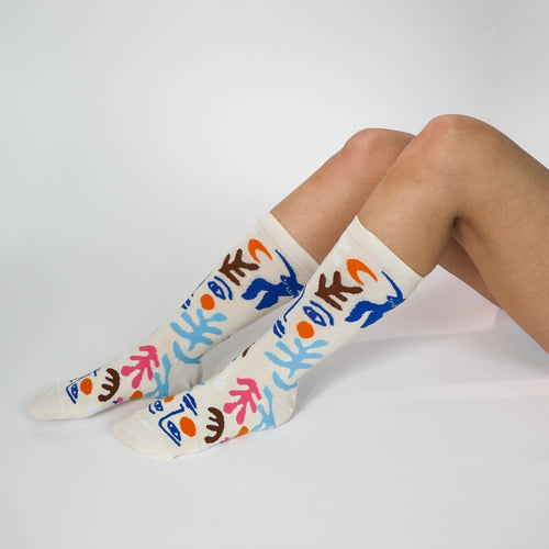 Cream Matisse-inspired crew socks with bold cut-paper figures and botanical shapes worn on feet by Yellow Owl Workshop