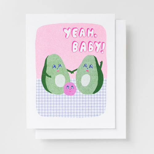 Risograph greeting card with two illustrated avocado characters holding hands with a small pink avocado pit between them on a pink and gingham background, text reads Yeah Baby in bold pink lettering