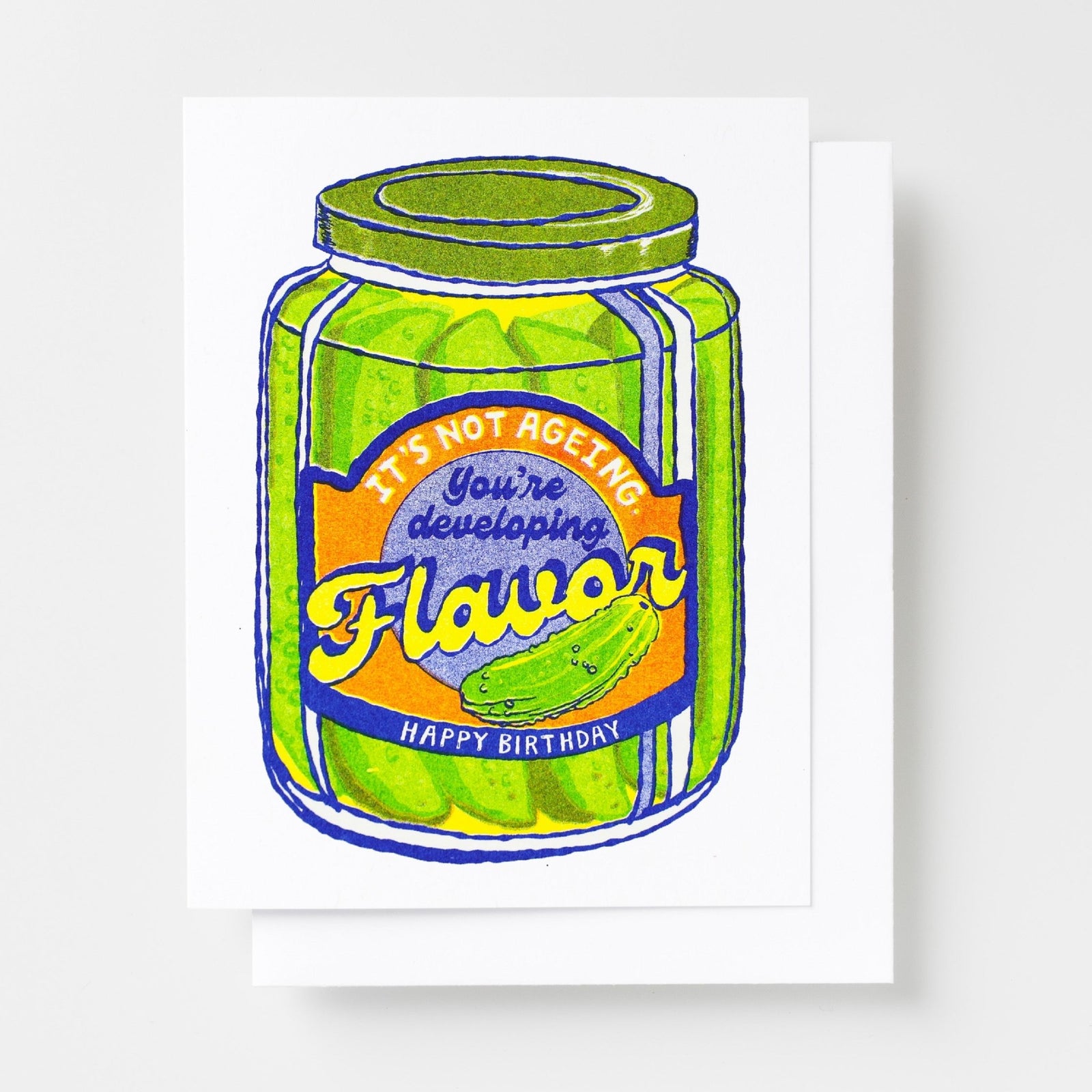 Risograph greeting card with an illustrated pickle jar with a label reading It's Not Ageing You're Developing Flavor Happy Birthday in green, yellow, and blue