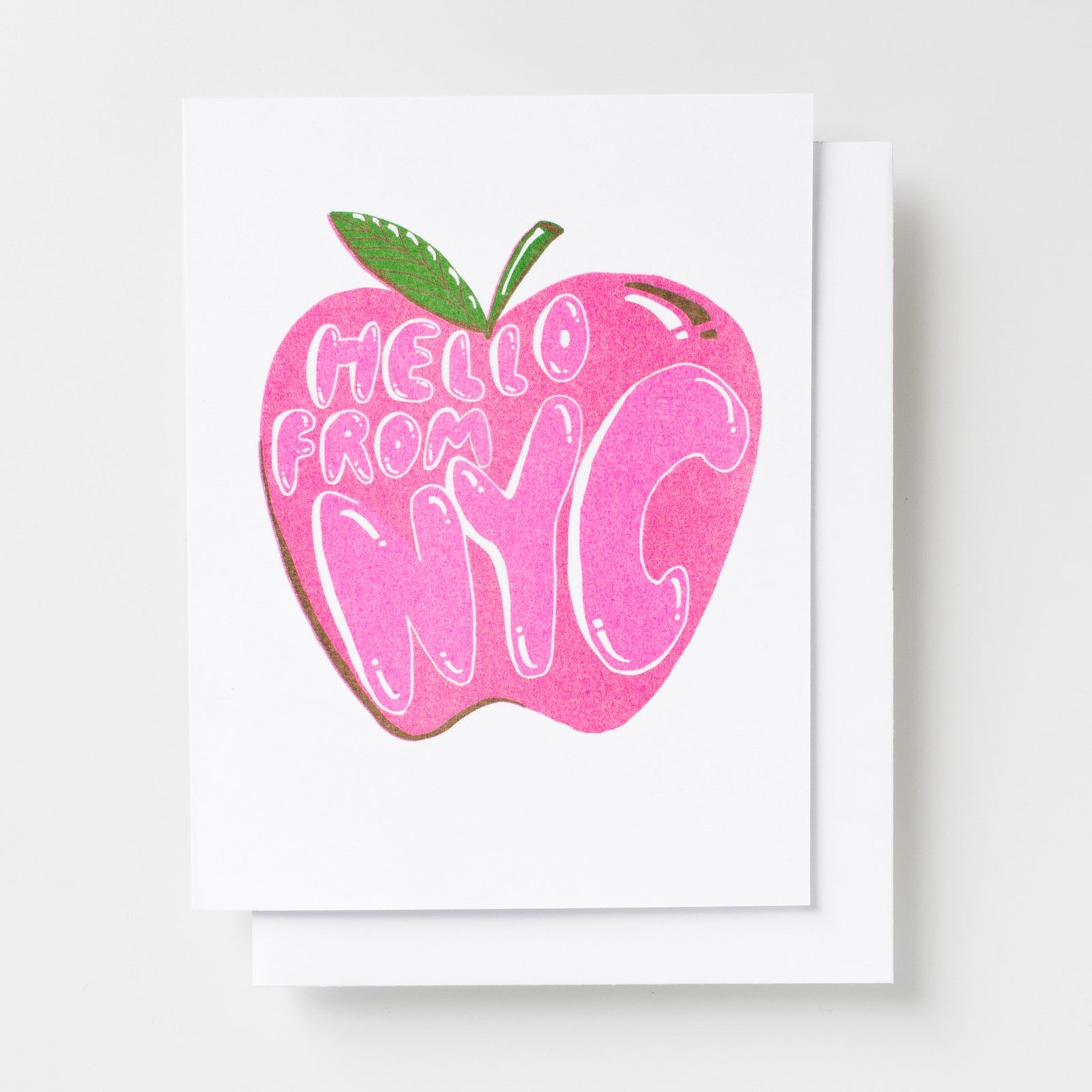 Risograph greeting card with a bold pink illustrated apple with text reading Hello From NYC in white bubble lettering with a green leaf stem on a white background