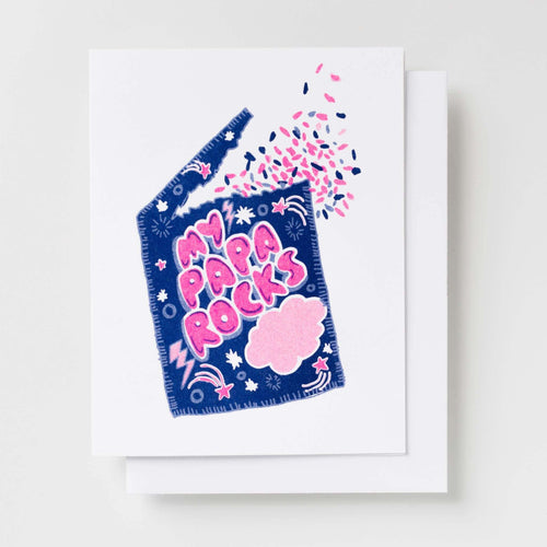 Risograph greeting card with an illustrated candy pouch designed like a Pop Rocks package reading My Papa Rocks in pink bubble lettering with stars, lightning bolts, and popping candy bursting from the top