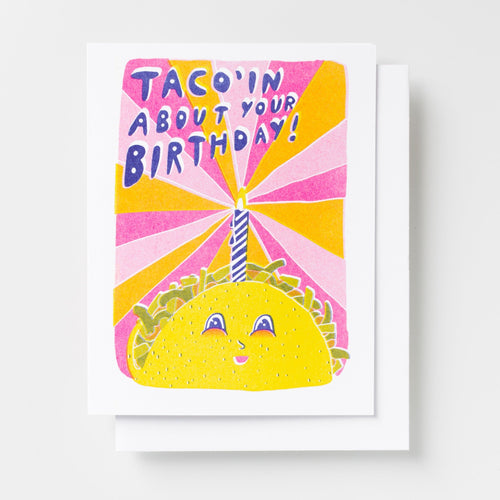 Risograph greeting card with a smiling taco character and birthday candle on a sunburst background in pink, yellow, and orange, text reads Taco'in About Your Birthday in bold blue lettering